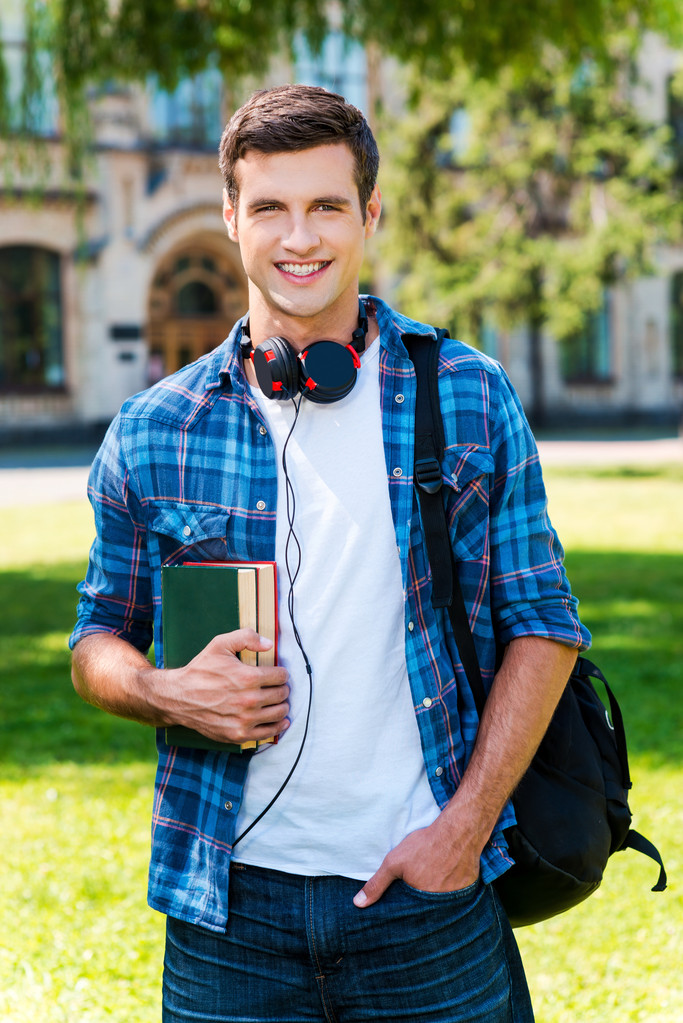 Молодой человек держит книги и улыбается
 - Фото, изображение