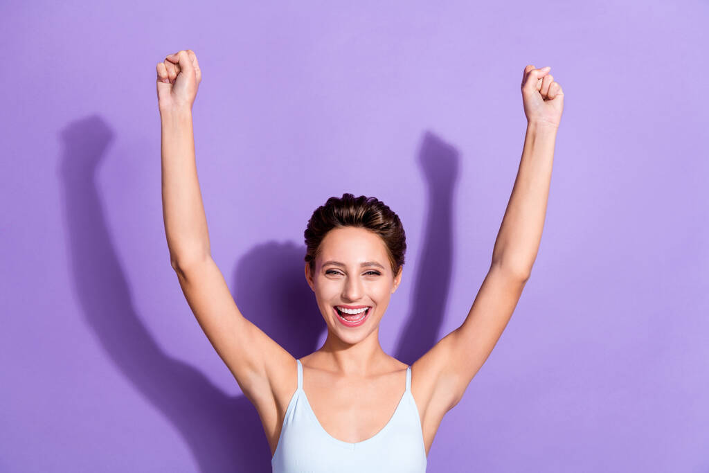 Photo portrait girl in blue top smiling gesturing like winner isolated pastel violet color background - Photo, Image