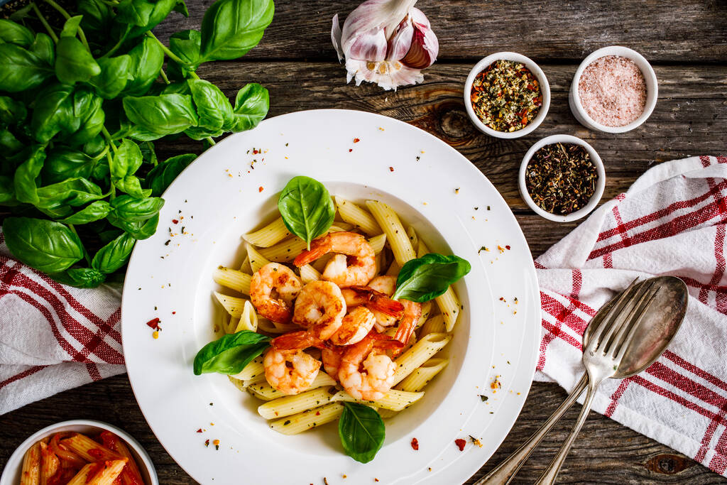 Penne with fried prawns on wooden background - Photo, Image