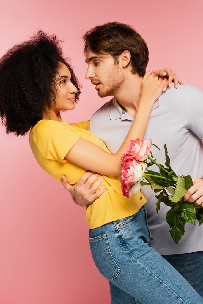 nuori mies tuoreita ruusuja käsittää tyytyväinen latino tyttöystävä eristetty vaaleanpunainen - Valokuva, kuva