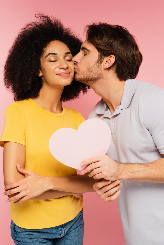 чоловік з папером вирізав серце цілує щасливу свою латиноамериканську дівчину ізольовано на рожевому
 - Фото, зображення