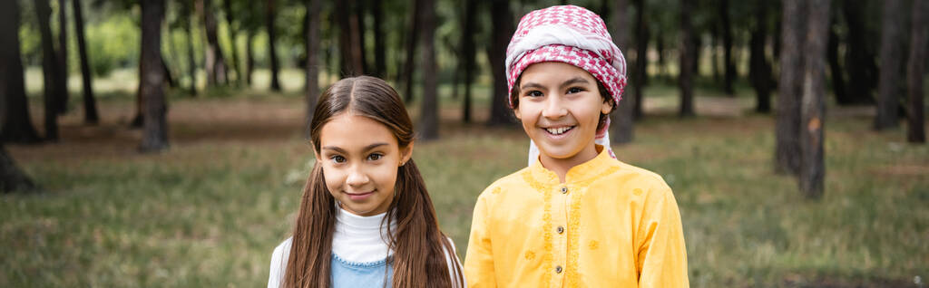 Улыбающиеся мусульманские дети смотрят на камеру в парке, баннер  - Фото, изображение