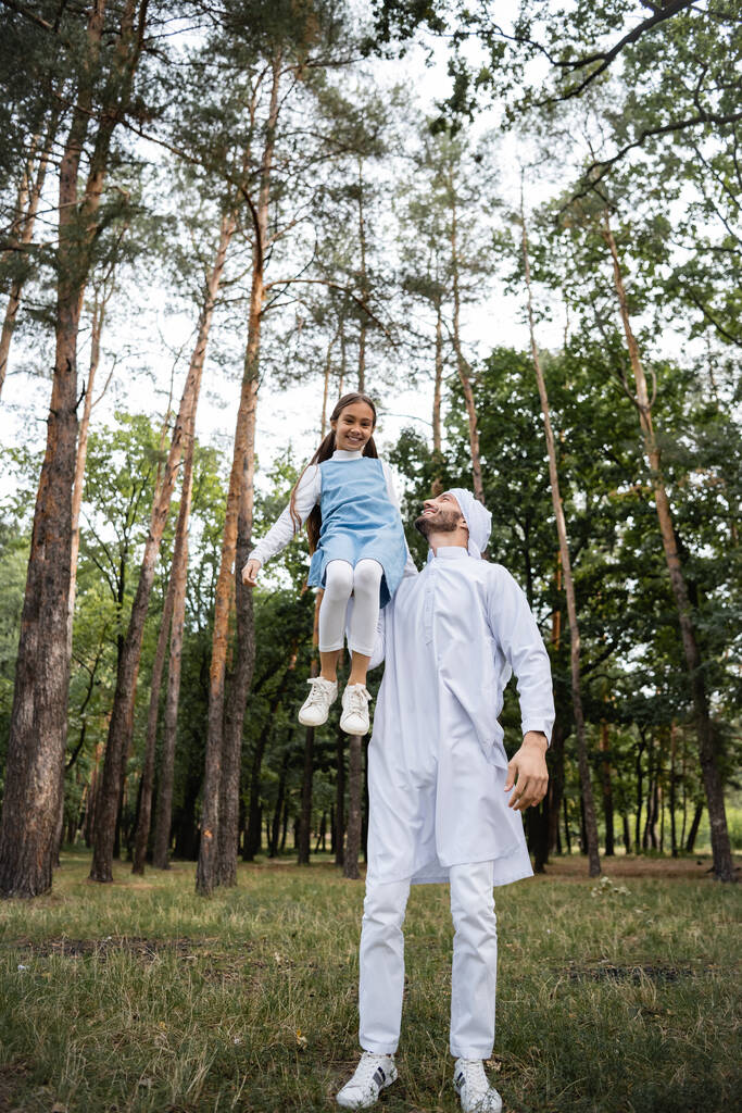 Muzułmanin trzyma uśmiechniętą córkę w parku  - Zdjęcie, obraz