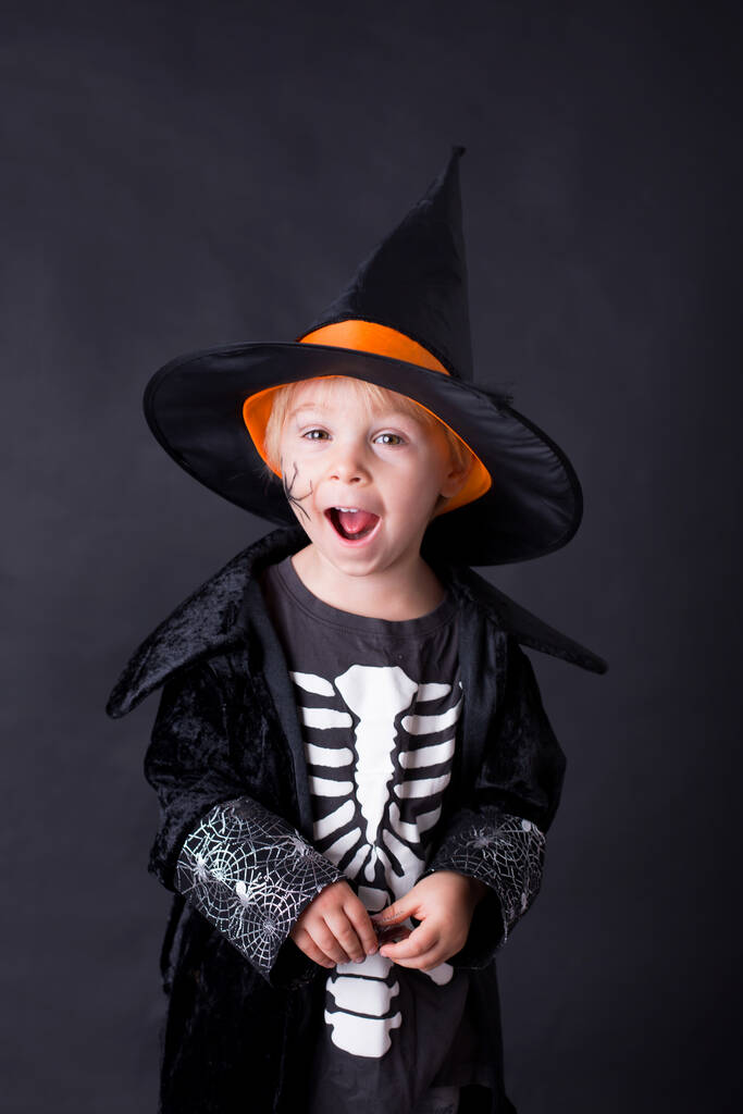 Dítě, oblečené na Halloween, hraje doma, izolovaný obraz na černém pozadí - Fotografie, Obrázek