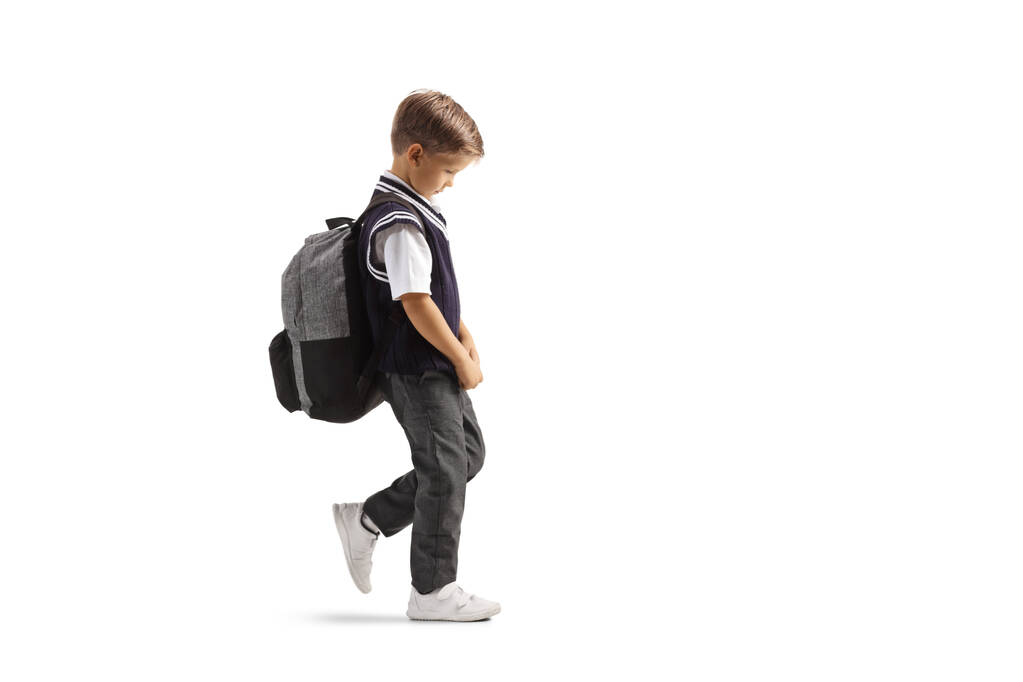 Full length profil záběr chlapce ve školní uniformě chůze smutné izolované na bílém pozadí - Fotografie, Obrázek