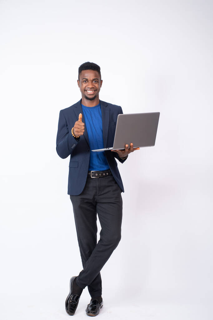 Um homem de negócios africano num fato com um portátil em frente a uma parede branca - Foto, Imagem