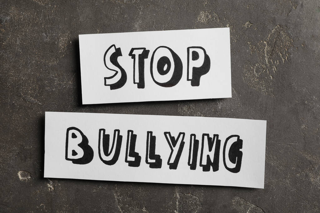 Trozos de papel con texto Stop Bullying en la superficie de piedra gris, plano lay - Foto, Imagen