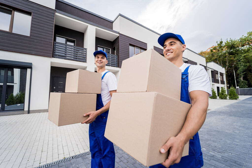 Twee verhuisbedrijf werknemers lossen dozen in nieuwe klanten huis - Foto, afbeelding