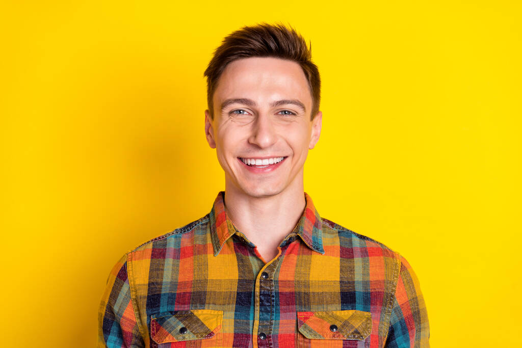 Portrait von attraktiven fröhlichen braunhaarigen Kerl gute Laune tragen kariertes Hemd isoliert über leuchtend gelben Farbhintergrund - Foto, Bild