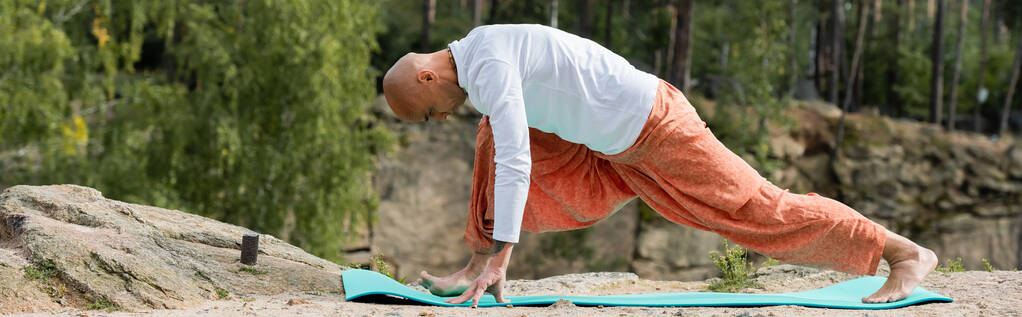 vista lateral de buddhist en sudadera blanca practicando yoga en pose de zancada creciente, pancarta - Foto, Imagen