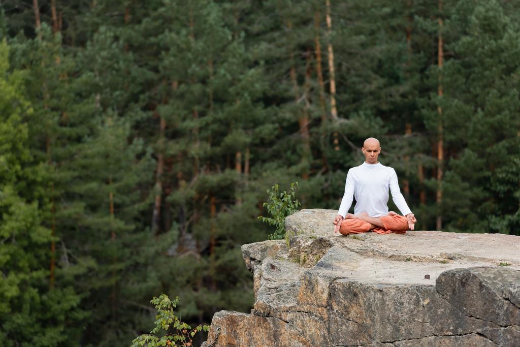 буддист в білому светрі, роздумуючи в позі лотоса на скелі в лісі
 - Фото, зображення