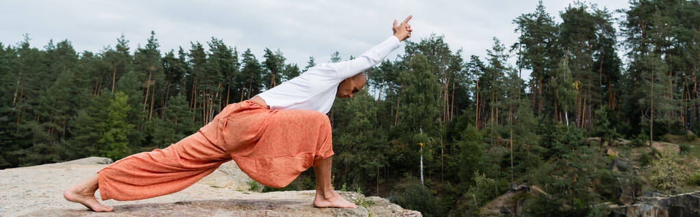 vista lateral de buddhist en sudadera blanca practicando crescent lunge pose, banner - Foto, imagen