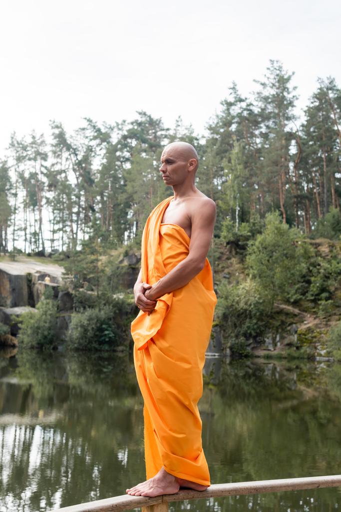 άποψη πλήρους μήκους ξυπόλυτος βουδιστής διαλογισμό, ενώ στέκεται σε ξύλινο φράχτη - Φωτογραφία, εικόνα