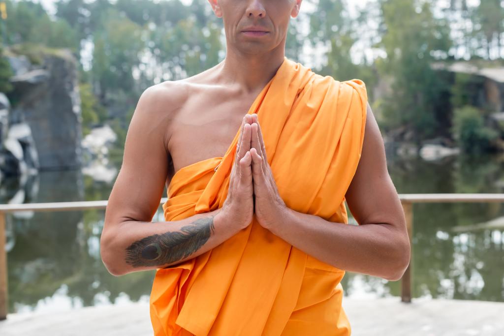 przycięty widok wytatuowanego buddysty medytującego z modlącymi się rękami na zewnątrz - Zdjęcie, obraz