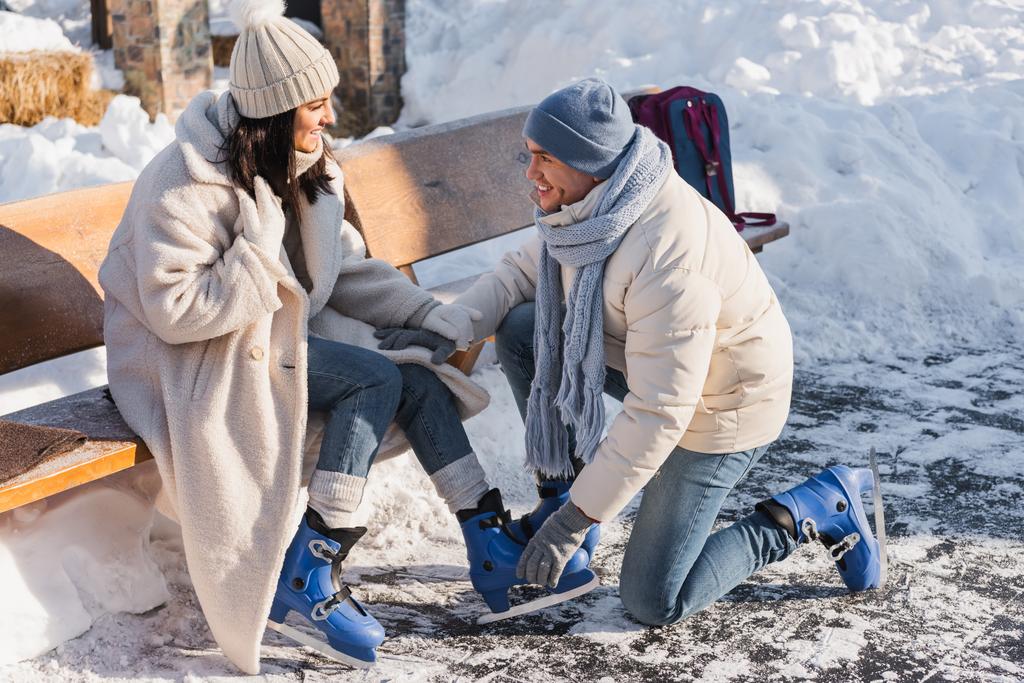 feliz hombre usando patines de hielo en la mujer alegre en sombrero de invierno - Foto, imagen