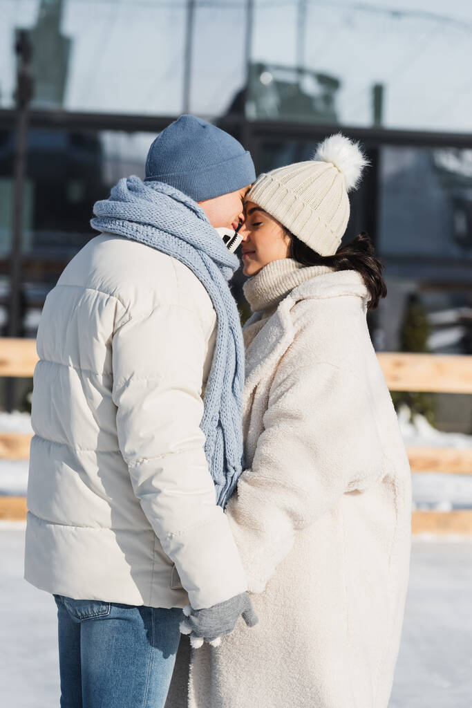 junges glückliches Paar in Wintermützen küsst sich draußen  - Foto, Bild