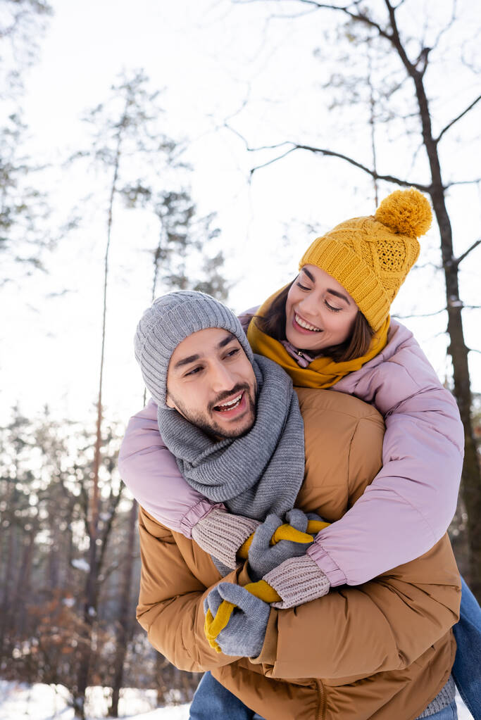 Cheerful woman hugging boyfriend in winter park  - Photo, Image