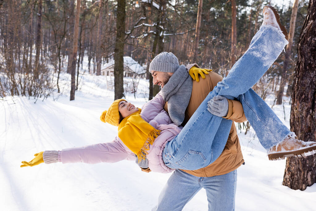 Uśmiechnięta para w kapeluszach bawiąca się w zimowym parku  - Zdjęcie, obraz