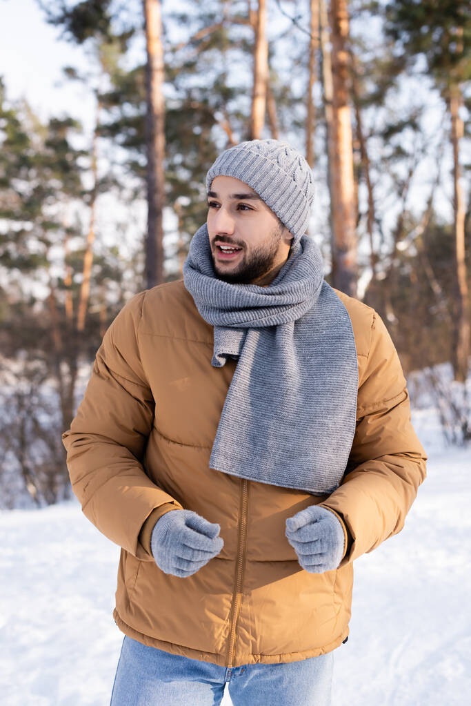 Χαμογελώντας άντρας με ζεστά ρούχα κοιτάζοντας μακριά στο πάρκο - Φωτογραφία, εικόνα