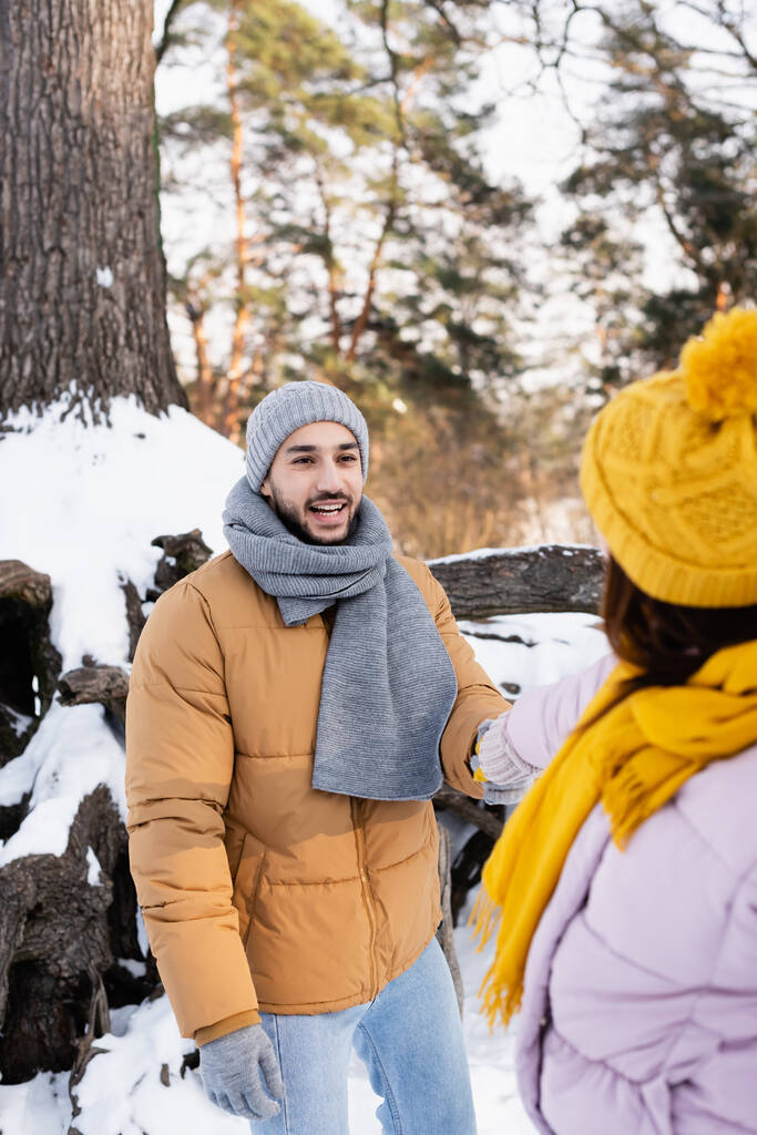 Smiling man holding hand of blurred girlfriend in winter park  - Photo, Image