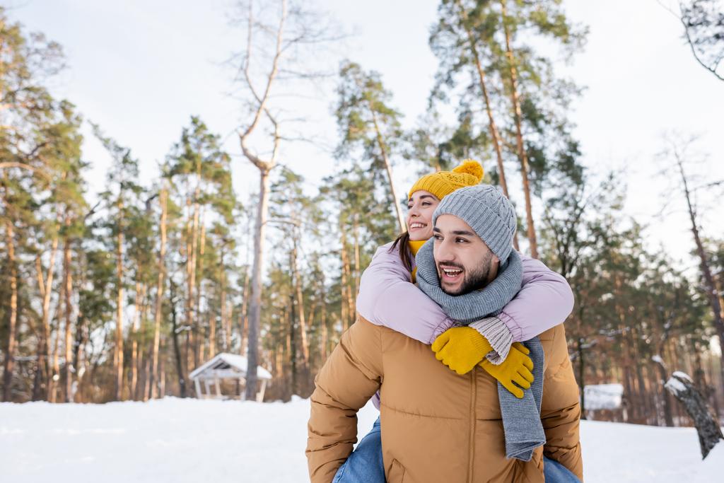 Улыбающаяся женщина обжимается с парнем в зимнем парке  - Фото, изображение