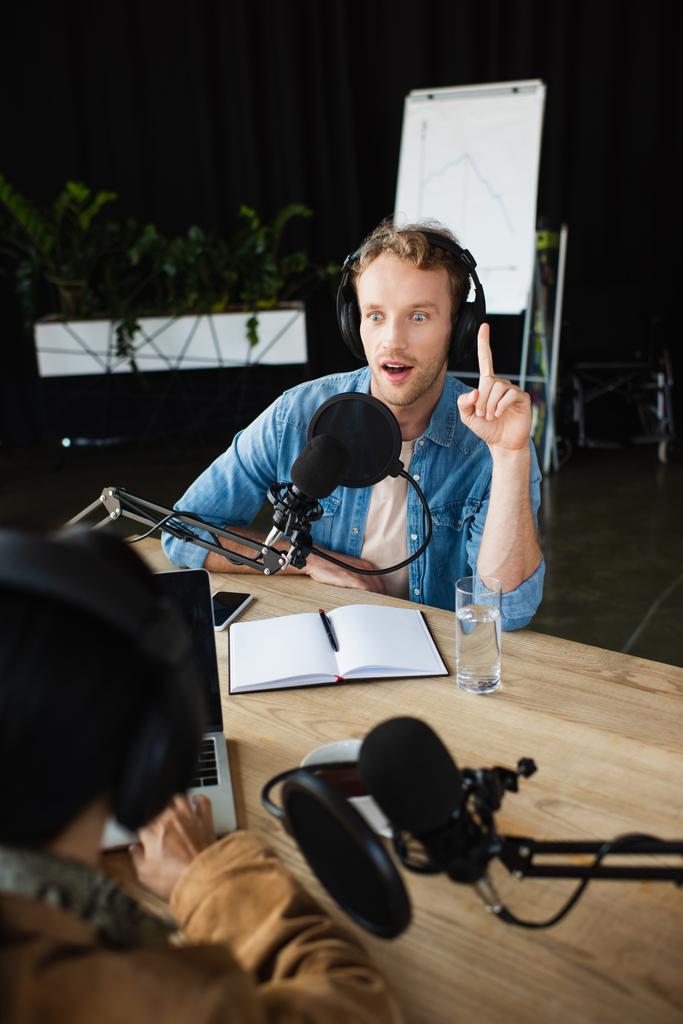 κατάπληκτος ραδιοφωνικός οικοδεσπότης σε ακουστικά που έχουν ιδέα κατά τη διάρκεια podcast - Φωτογραφία, εικόνα