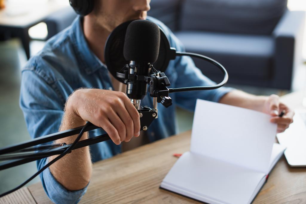Radyo sunucusunun kablosuz kulaklıklarıyla stüdyodaki mikrofon standına dokunuşunun kısmi görüntüsü  - Fotoğraf, Görsel