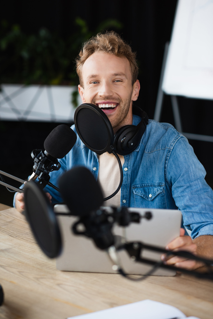 positiver Radiomoderator mit Kopfhörer lächelt im Podcast-Studio  - Foto, Bild