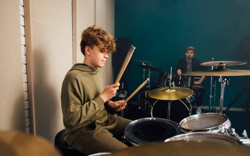 Хлопчик вчиться грати на барабанах. Музичний урок з вчителем
. - Фото, зображення