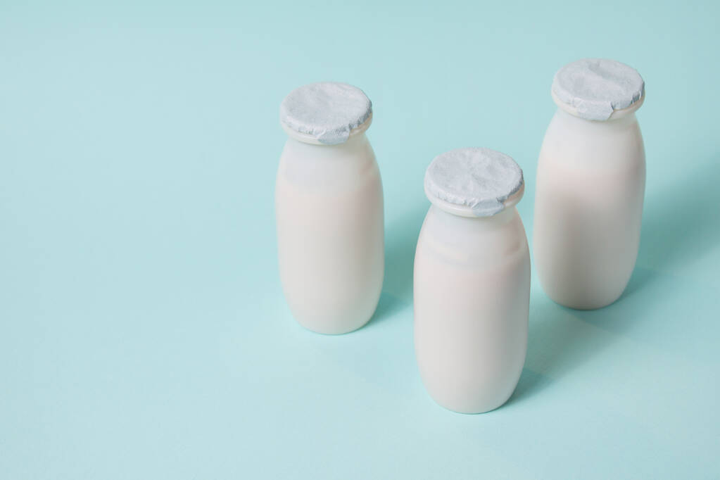 プロバイオティクスとプレバイオティクスを含むボトル乳製品は水色の背景で飲みます. - 写真・画像