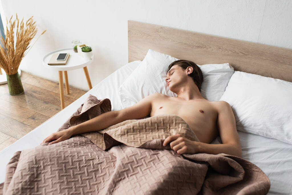 Genç ve üstsüz bir transseksüel evde yatakta uyuyor. - Fotoğraf, Görsel
