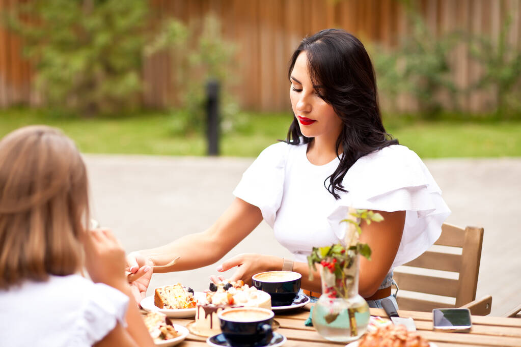 Moeder met tiener meisje zitten in cafe terras en hebben een ontbijt of tak - Foto, afbeelding