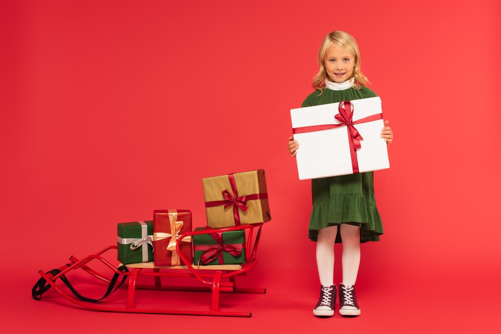 täyspitkä näkymä tyylikäs tyttö läsnä lähellä kelkka lahjapakkaukset punainen - Valokuva, kuva
