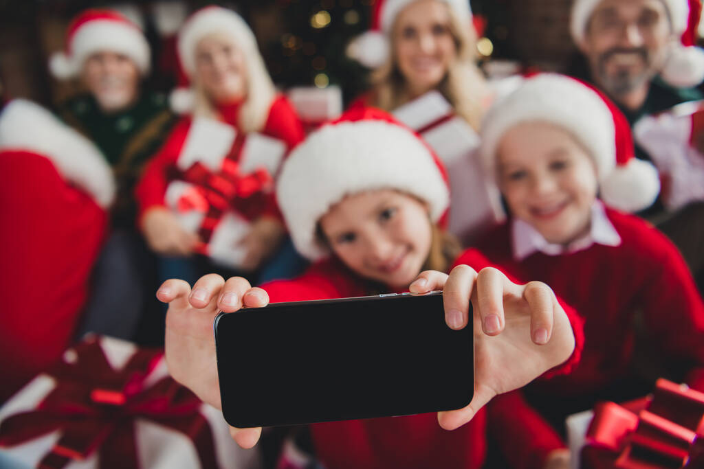 Πορτρέτο των ελκυστικών χαρούμενες οικογενειακές δαπάνες ημέρα Δεκέμβριος φορώντας καπέλα κρατώντας δώρα λήψη selfie στο σπίτι πατάρι σε εσωτερικούς χώρους - Φωτογραφία, εικόνα