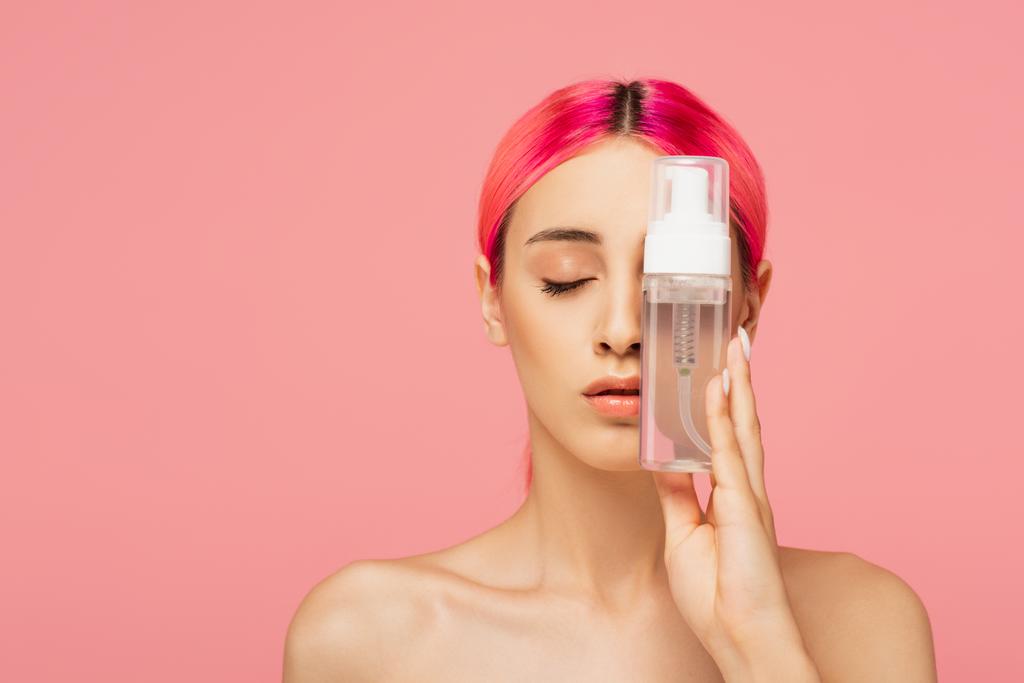 giovane donna con capelli tinti e occhi chiusi bottiglia con prodotto detergente isolato su rosa  - Foto, immagini