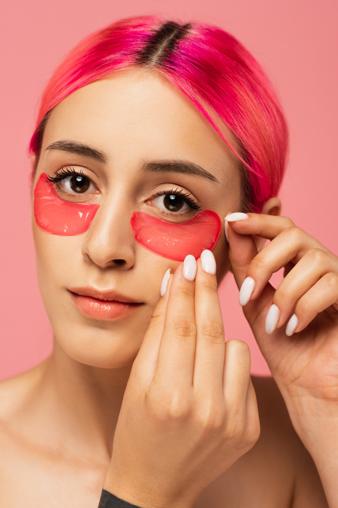 bella giovane donna con i capelli colorati applicando toppe oculari di collagene isolato su rosa  - Foto, immagini