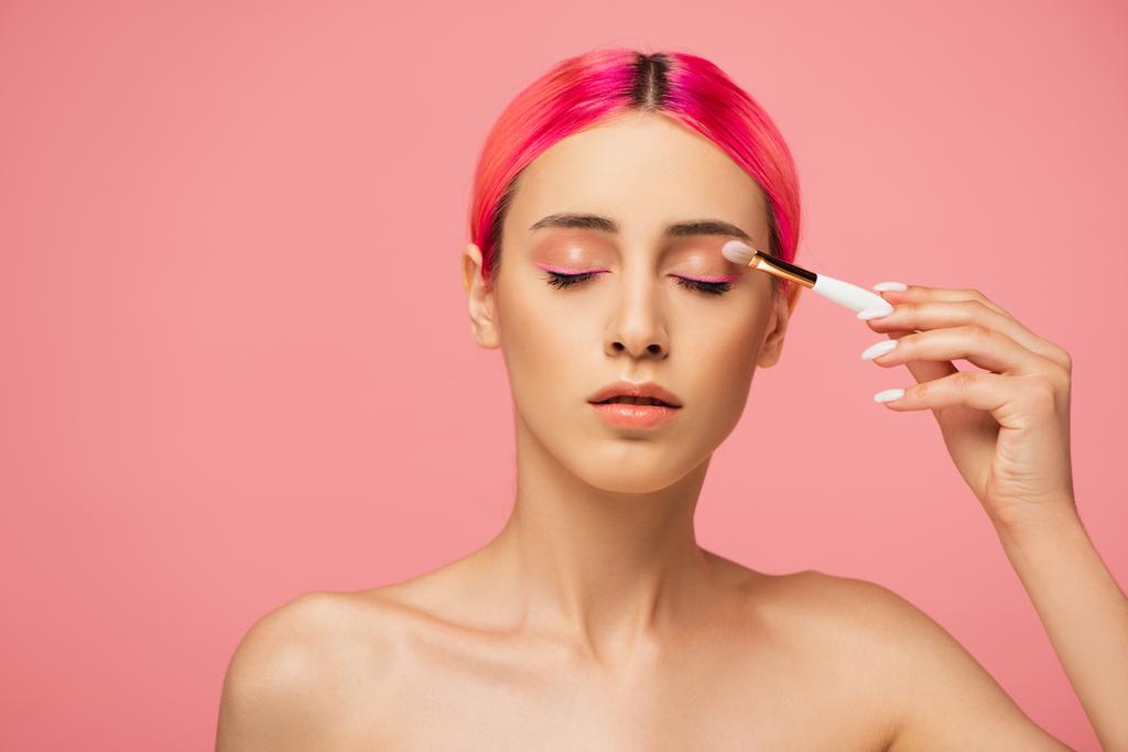 junge Frau mit geschlossenen Augen, die Lidschatten isoliert auf rosa anwendet  - Foto, Bild
