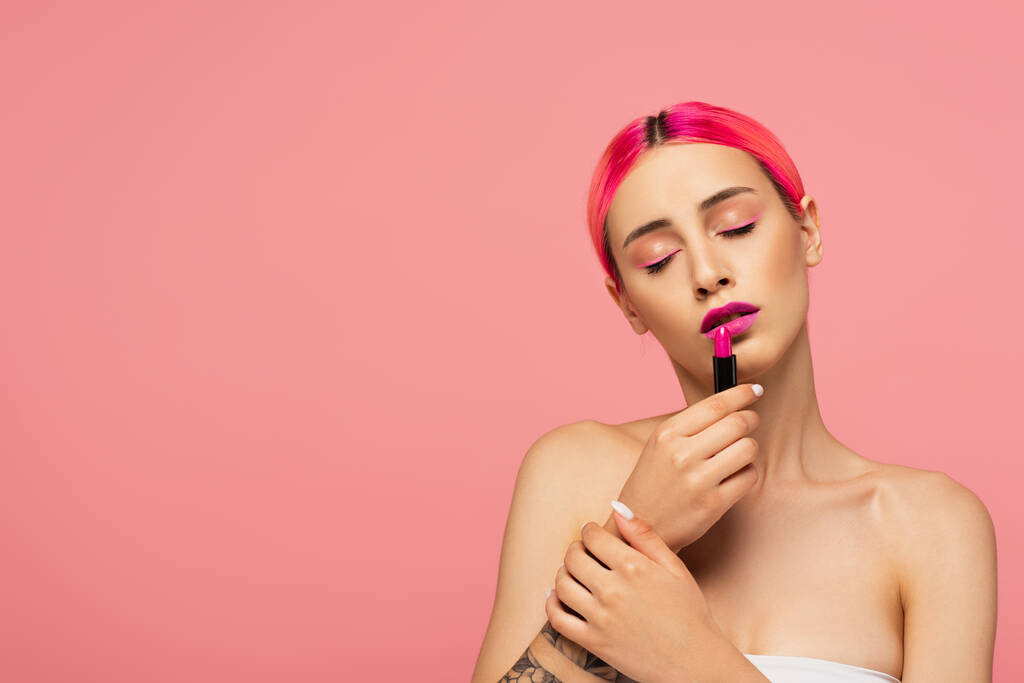 fiatal nő festett haj és csukott szemmel alkalmazó rúzs elszigetelt rózsaszín  - Fotó, kép