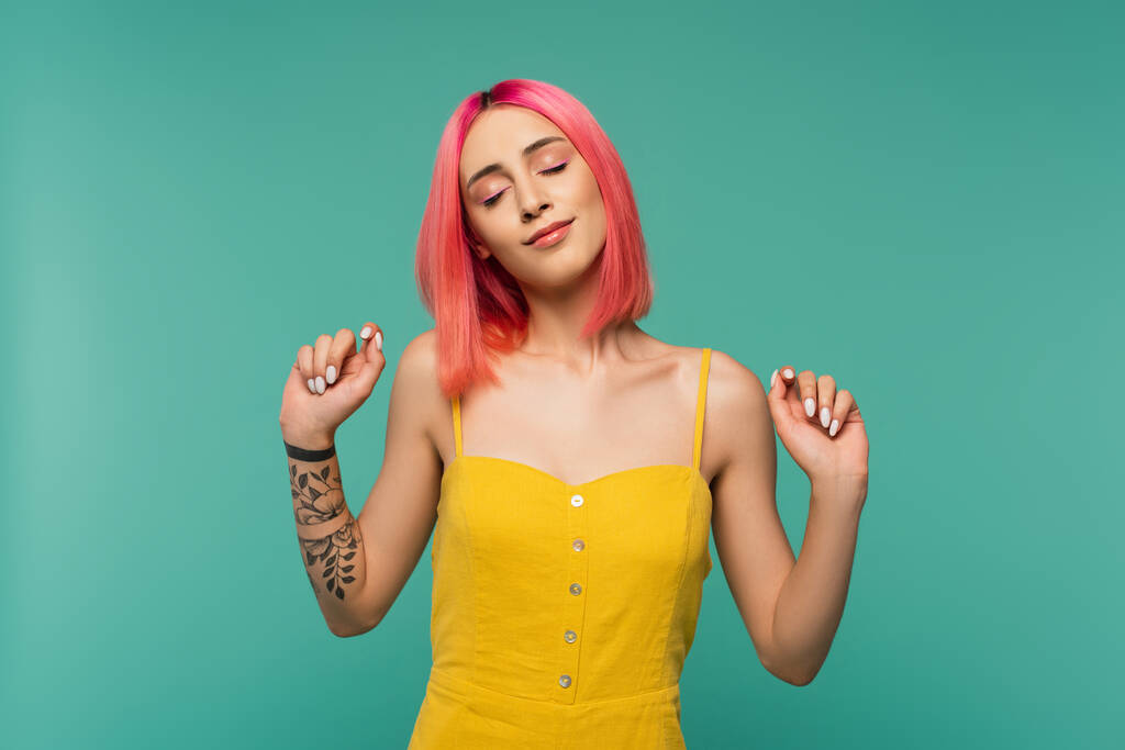 tetovált fiatal nő rózsaszín festett haj és csukott szemmel elszigetelt türkiz - Fotó, kép