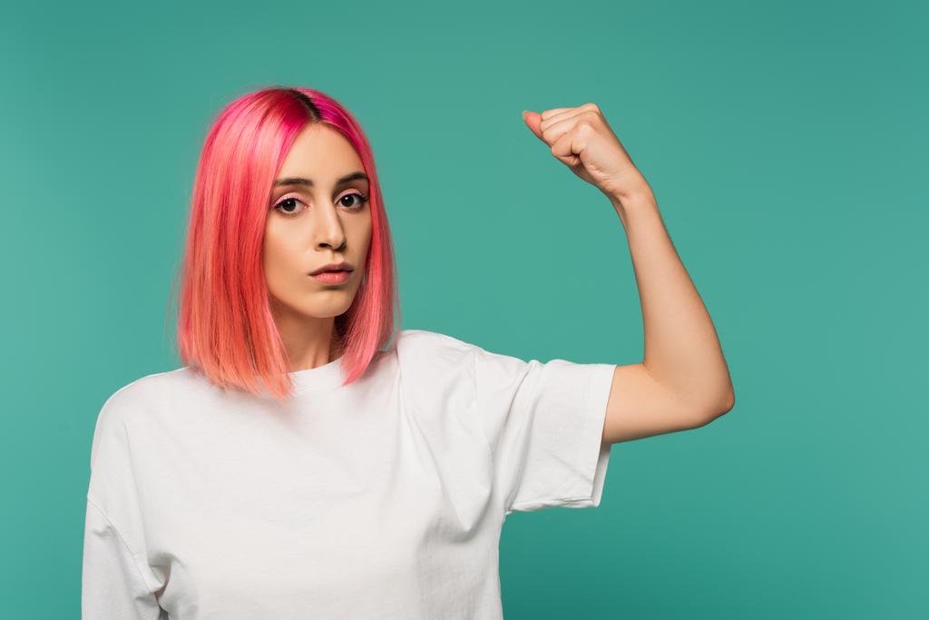 δυνατή νεαρή γυναίκα με ροζ βαμμένα μαλλιά που δείχνει τους μυς που απομονώνονται στο μπλε - Φωτογραφία, εικόνα