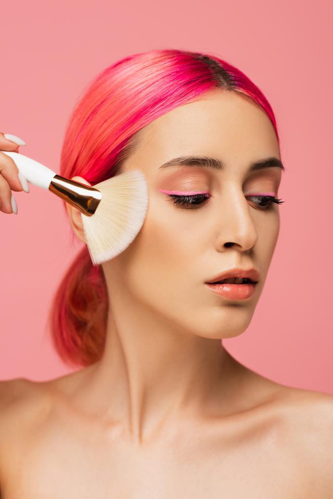 όμορφη νεαρή γυναίκα με πολύχρωμα μαλλιά που κατέχουν καλλυντική βούρτσα απομονώνονται σε ροζ  - Φωτογραφία, εικόνα