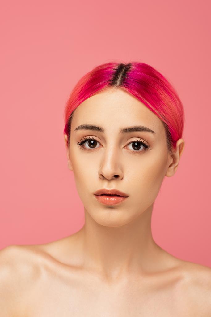 ładna młoda kobieta z kolorowymi włosami i makijaż patrząc na aparat odizolowany na różowy  - Zdjęcie, obraz