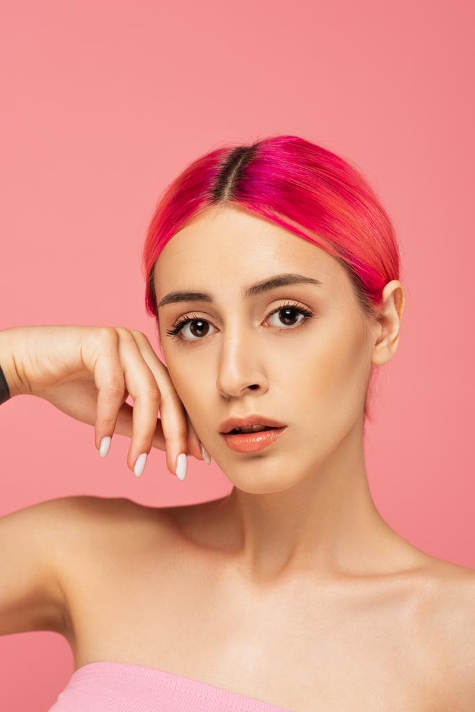 bonita mujer joven con el pelo colorido y los hombros desnudos mirando a la cámara aislada en rosa  - Foto, Imagen