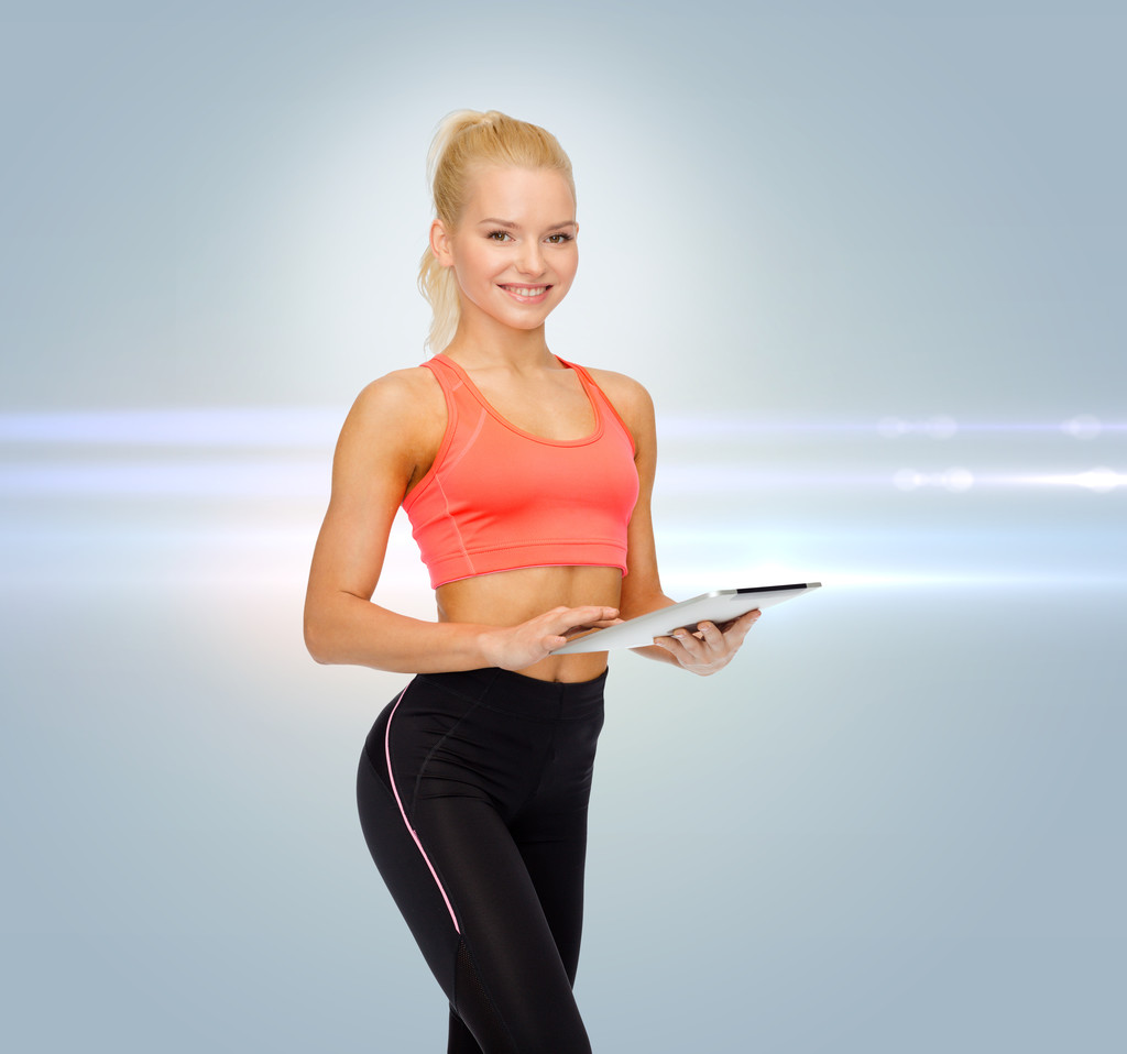 улыбающаяся спортивная женщина с планшетным компьютером
 - Фото, изображение