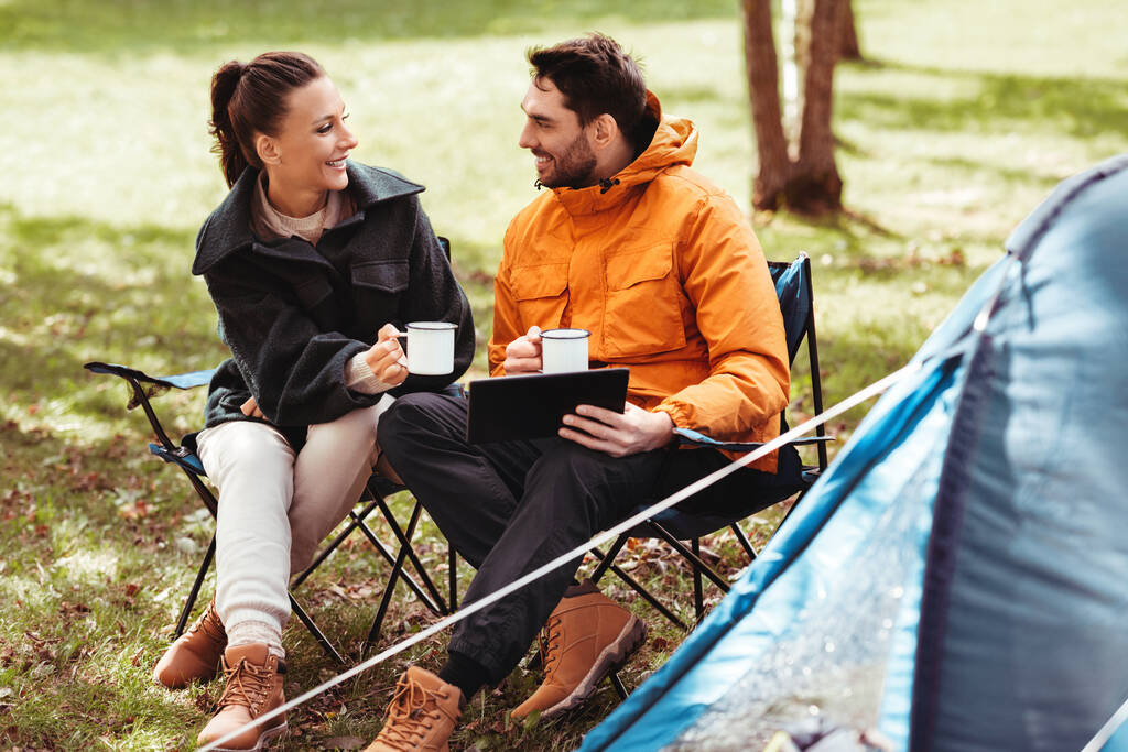 テントキャンプでタブレットPCでお茶を飲むカップル - 写真・画像