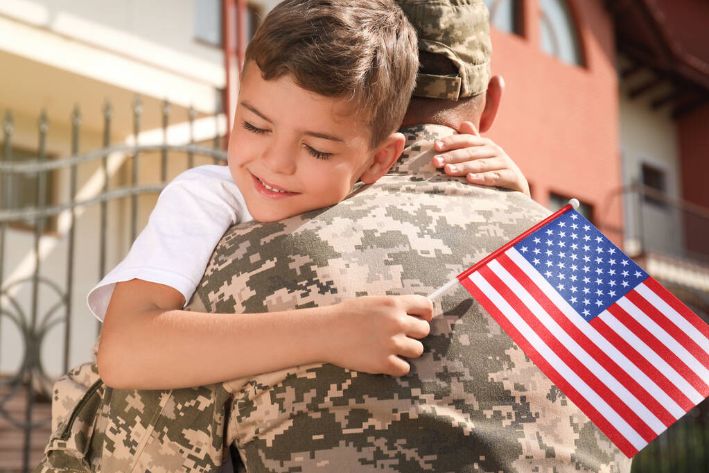 兵士と彼の息子アメリカの国旗を屋外で抱きしめる - 写真・画像
