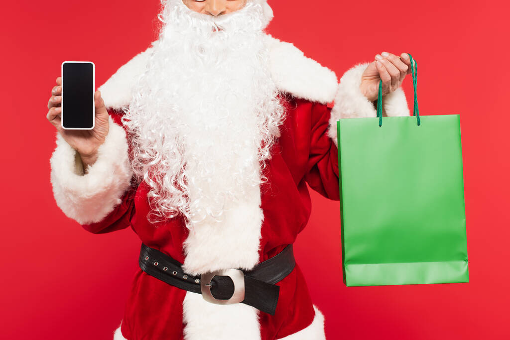 Vágott kilátás Santa Claus gazdaság okostelefon és bevásárló táska elszigetelt piros  - Fotó, kép