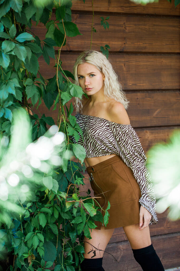 Portrait of young blonde woman posing on a wooden wall background - Photo, Image