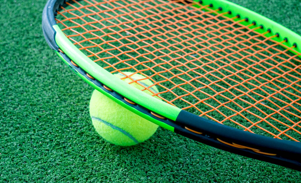 テニスボールとラケットが緑のコートの上に横になって. - 写真・画像