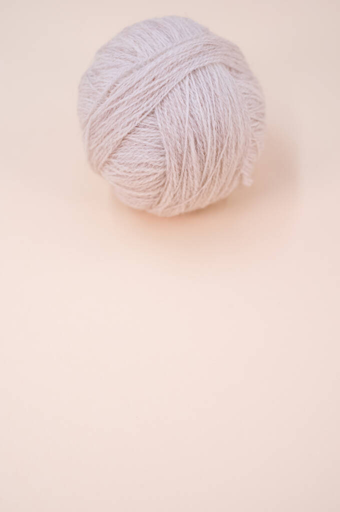 Una toma vertical de hilo gris aislado sobre un fondo beige con espacio de texto - Foto, Imagen